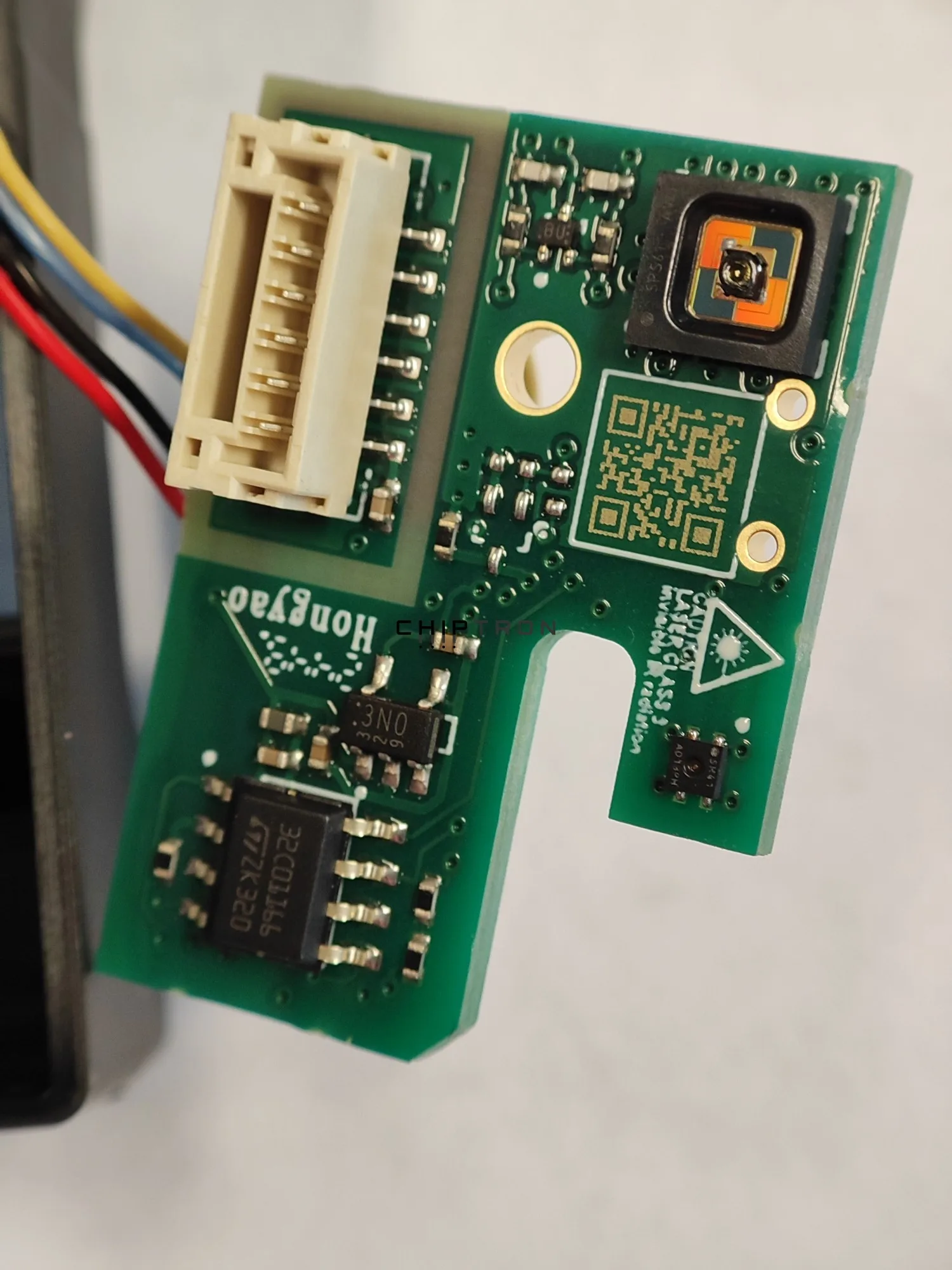 Close-up of the green SEN66 board with its connector, particulate sensor, and other components